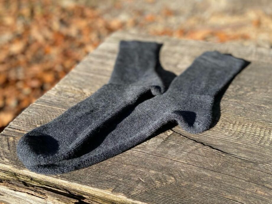 Woolpower socks 400 - grey auf einer holzbank